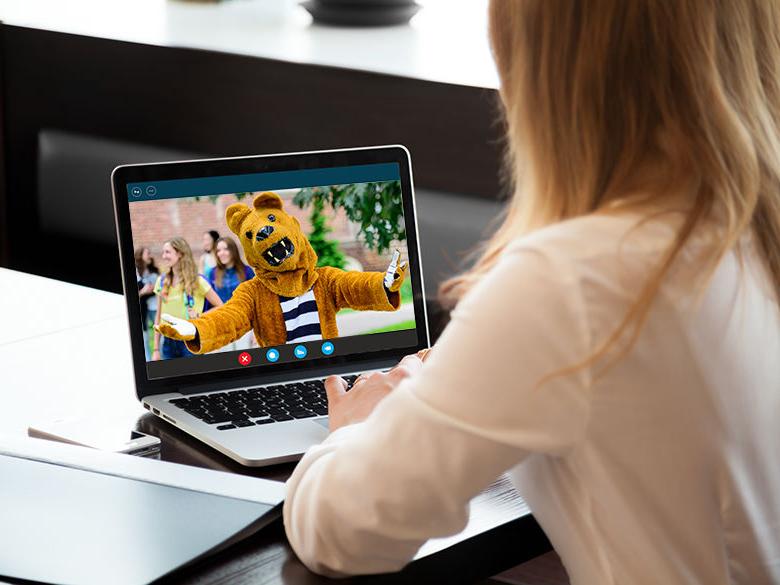 A woman having a virtual visit with the Nittany Lion on her laptop