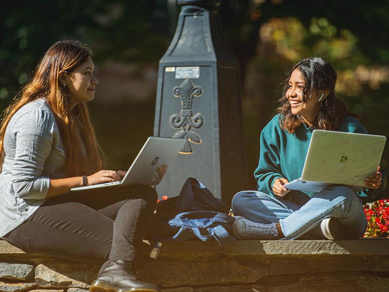 Two students sitting near the railroad clock on campus