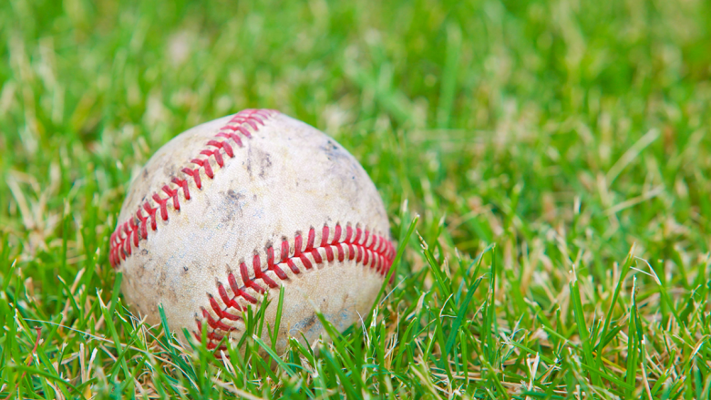 A baseball sitting in a field of grass